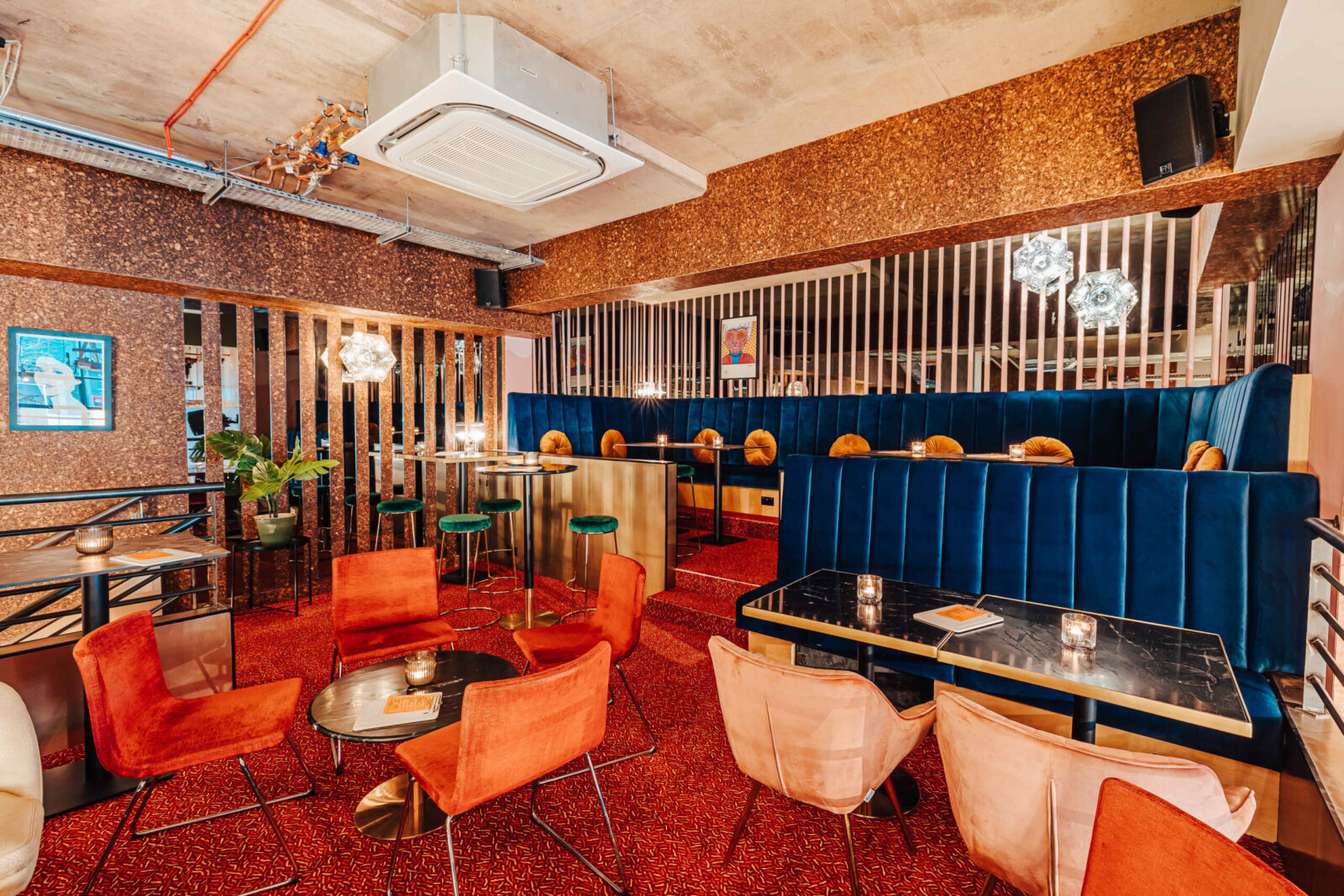 Inside Someday: orange lounge chairs, blue booths and marble tables under the Mezzanine
