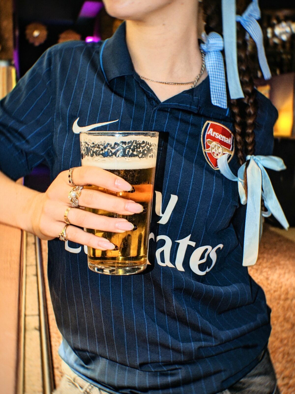 Fan in an Arsenal shirt holding a pint before the match at Someday